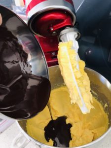 adding the melted chocolate to the butter and sugar